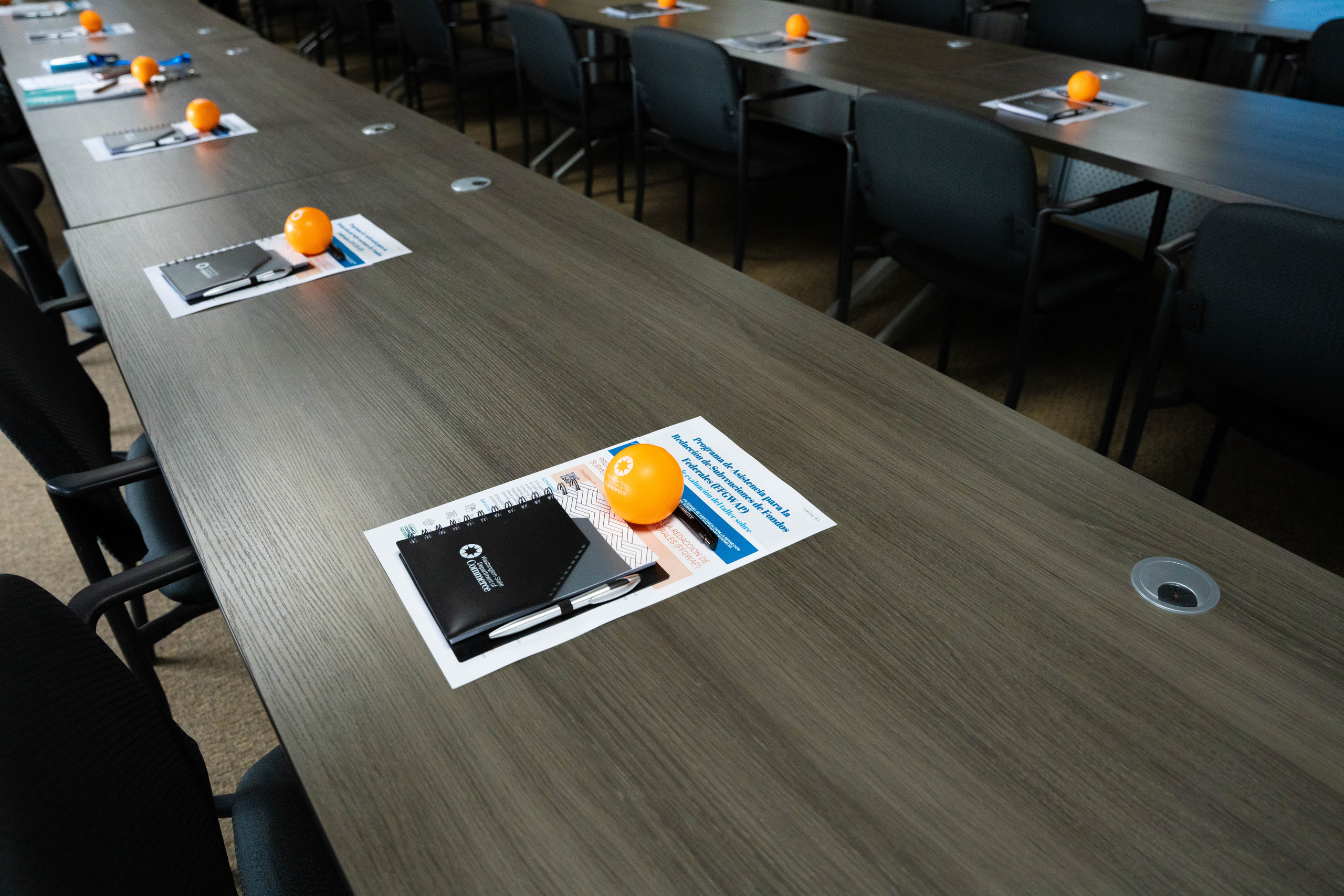 Workshop materials and an orange squishy ball on each seat along the training room tables, ready for attendees