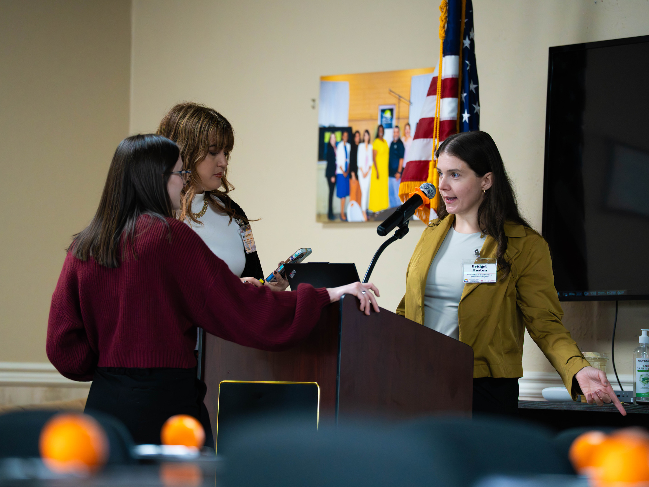 Three people talking at the podium before the workshop began, in the OIC of Washington training room